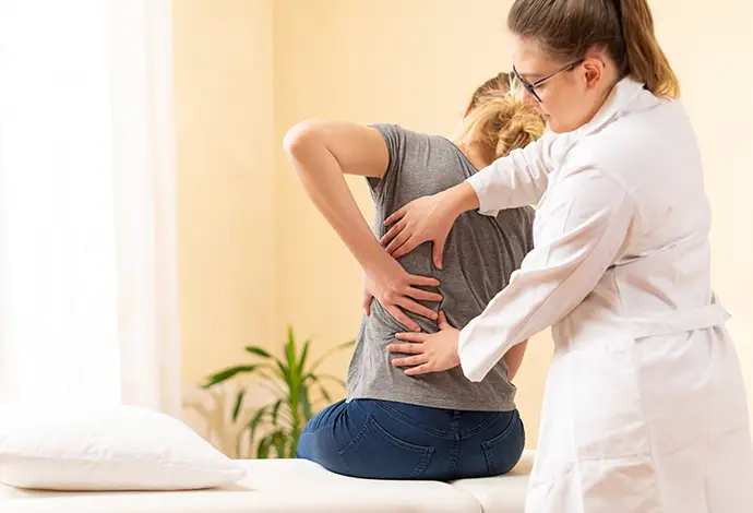 Female physiotherapist or a chiropractor examining patients back