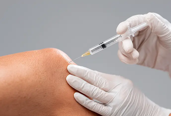 close up of gloved, professional's hands injecting Hyaluronic Acid to patient's knee at Saint Louis Pain Center